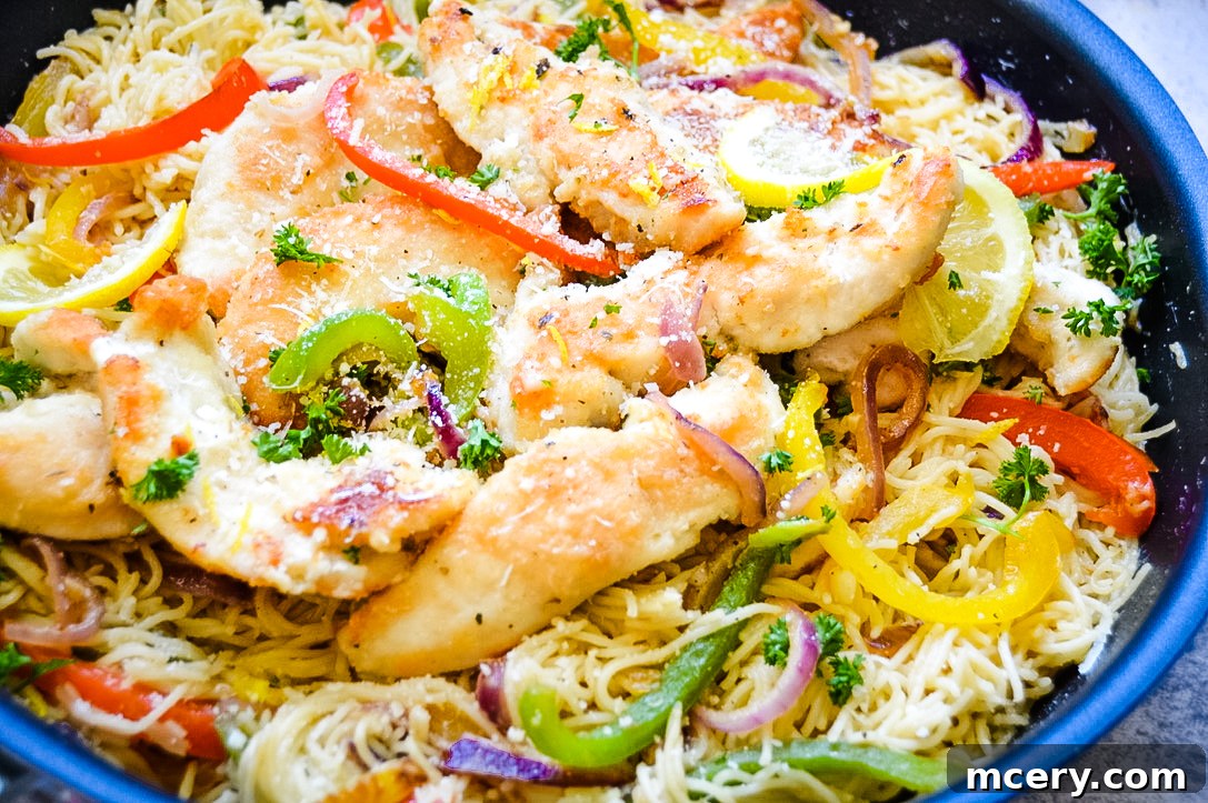 Lemon Garlic Chicken Scampi Pasta 2 Easy Chicken Scampi Pasta: A close-up shot of a plate of pasta with seared chicken, colorful bell peppers, and fresh parsley, all glistening with a buttery white wine sauce. Bright lemon wedges are placed on the side.