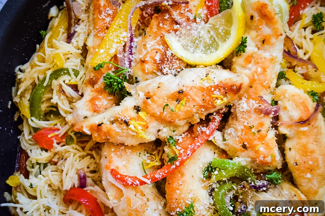 Lemon Garlic Chicken Scampi Pasta 4 Easy Chicken Scampi Pasta: A close-up of a skillet filled with chicken scampi pasta, featuring seared chicken, red and yellow bell peppers, onions, and pasta coated in a creamy sauce, garnished with parsley.