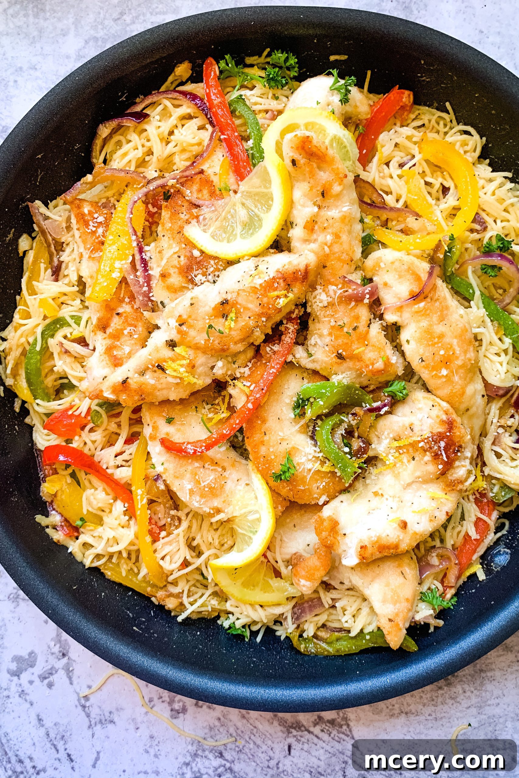 Lemon Garlic Chicken Scampi Pasta 6 EASY CHICKEN SCAMPI PASTA: A vertical shot of a vibrant plate of chicken scampi pasta, featuring seared chicken, colorful bell peppers, red onions, and fresh parsley, all glistening with a rich sauce.