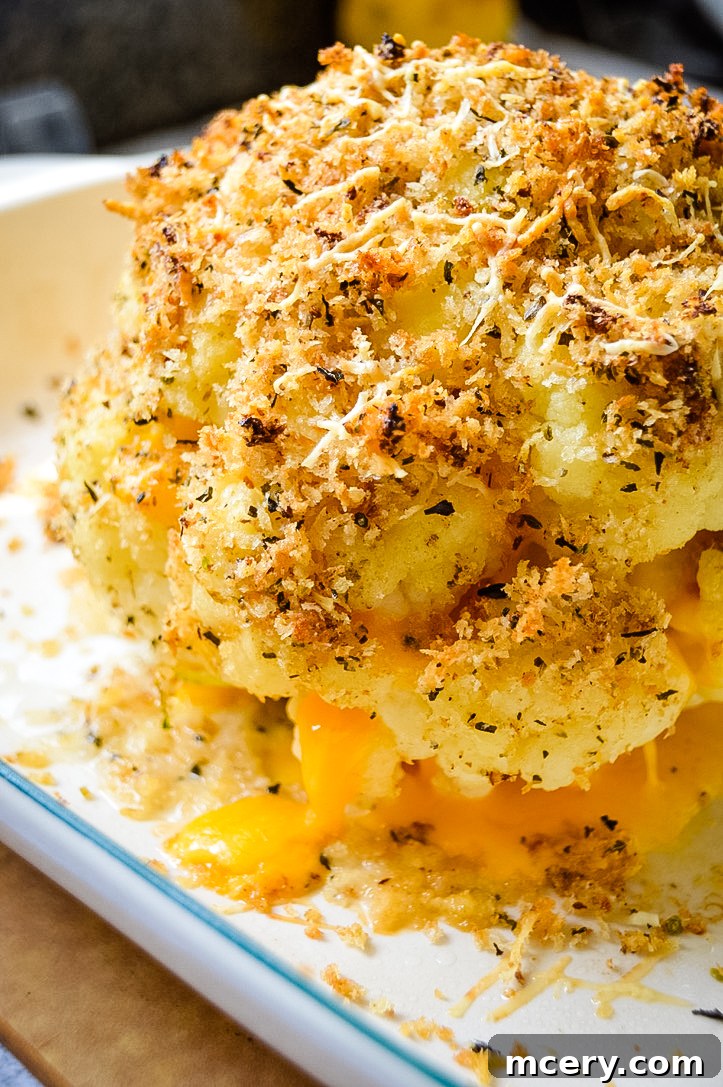 Golden Cheddar Stuffed Cauliflower 6 An appetizing close-up of a slice of the cheddar cheese stuffed cauliflower, revealing the melted cheese within the tender florets, with a golden Panko crust. This image is perfect for sharing on social media like Pinterest.