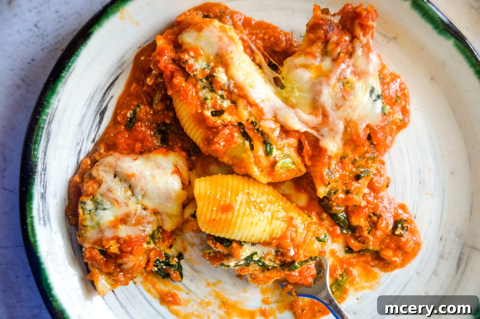 Spinach and Ricotta Stuffed Shells Bake 3 A wide shot of raw jumbo pasta shells on a baking sheet next to a bowl of creamy spinach and cheese filling. Essential ingredients are neatly arranged, ready for assembly, showcasing the fresh, vibrant components.