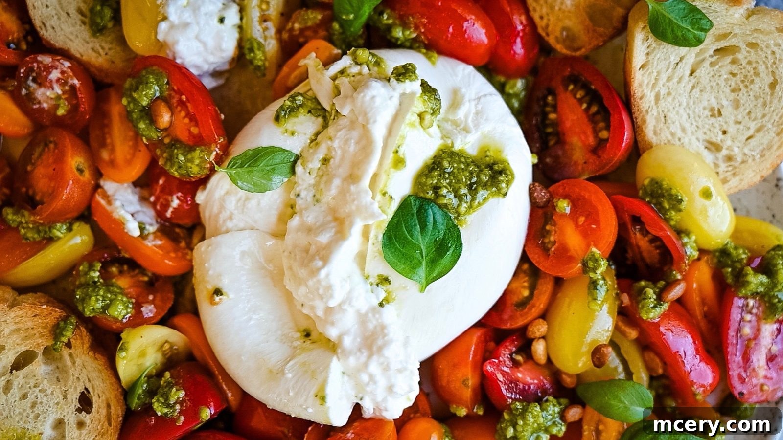 Velvety Burrata with Ripe Tomatoes and Fragrant Pesto 3 An overhead shot of Fresh Tomato and Burrata Salad with Pesto, featuring a large round of burrata cheese in the center, surrounded by an assortment of halved cherry tomatoes and splashes of bright green pesto. Fresh basil leaves and crunchy garlic toast add texture and color to the gourmet presentation.