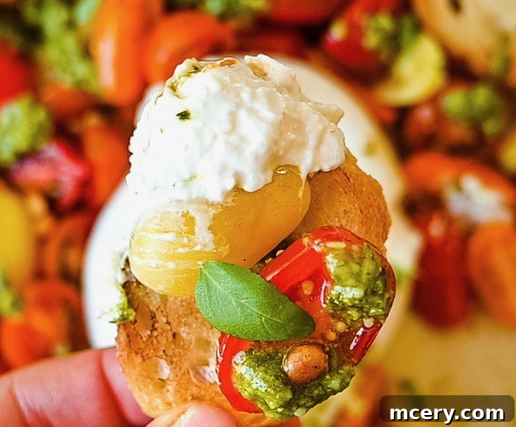 Velvety Burrata with Ripe Tomatoes and Fragrant Pesto 4 Close-up of the ingredients for Fresh Tomato and Burrata Salad with Pesto, showing halved cherry tomatoes drizzled with olive oil and seasoned, alongside a bowl of minced garlic, lemon halves, and a bottle of extra virgin olive oil, highlighting the freshness of the components.