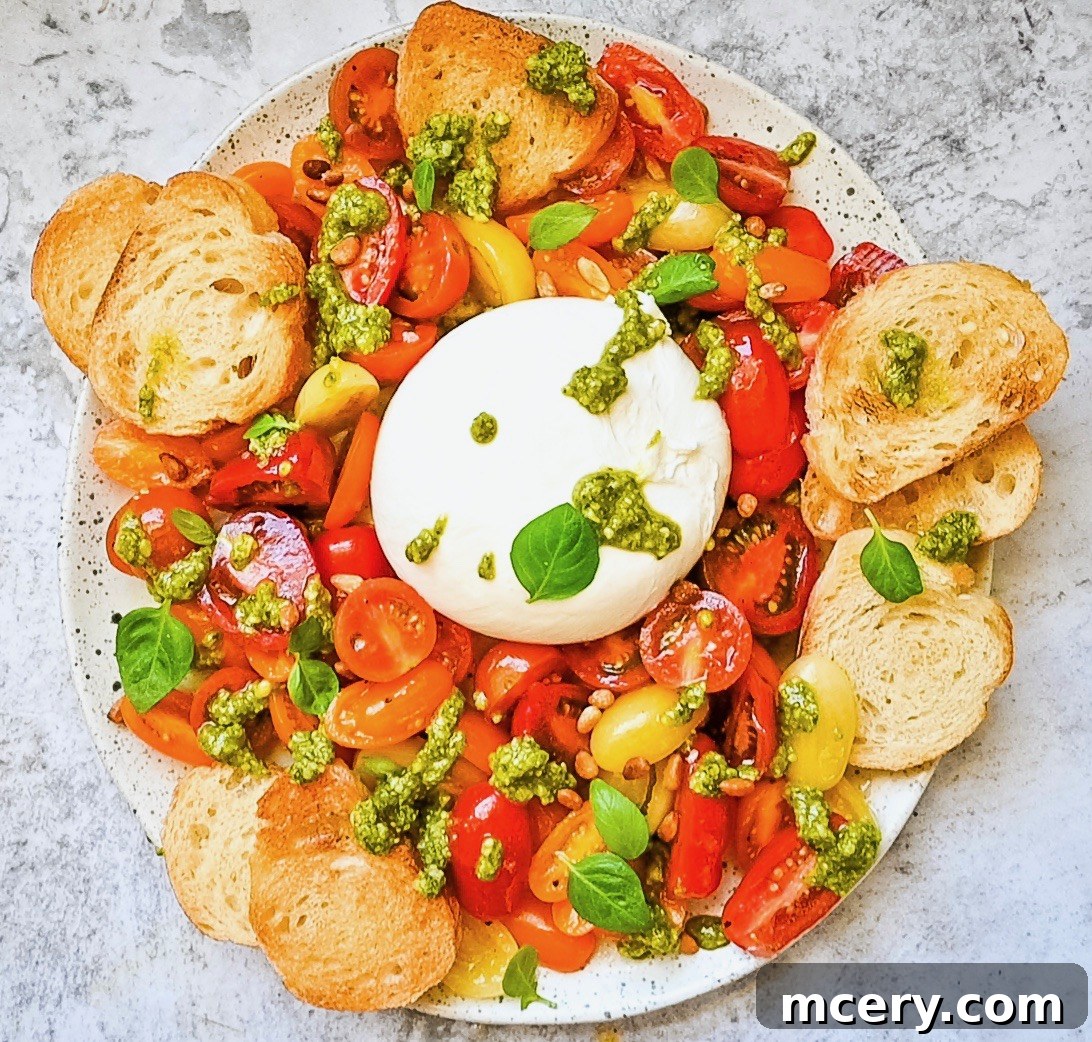 Velvety Burrata with Ripe Tomatoes and Fragrant Pesto 5 A close-up of Fresh Tomato and Burrata Salad with Pesto, beautifully arranged on a plate with fresh basil, pine nuts, and toasted garlic bread slices. The creamy burrata is nestled amongst colorful cherry tomatoes and generous drizzles of green pesto, ready to be enjoyed.