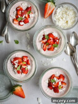 Strawberry chia seed pudding in glass jars topped with fresh strawberries.