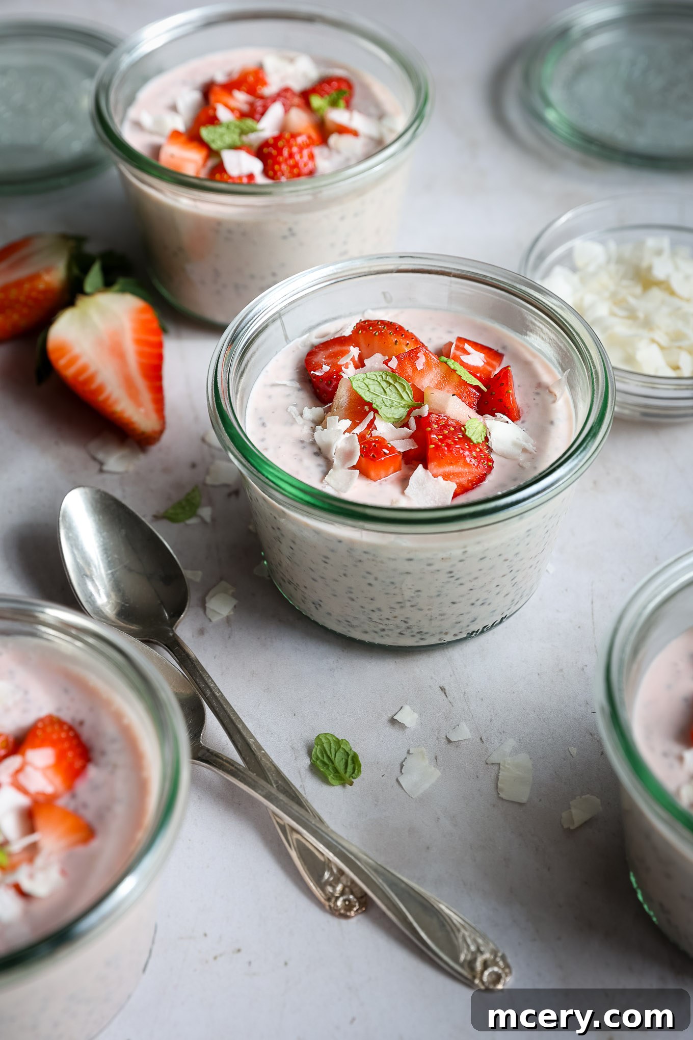 Delightful Strawberry Chia Pudding 8 A glass jar of chia seed pudding with a spoon, topped with coconut flakes, ready to eat.