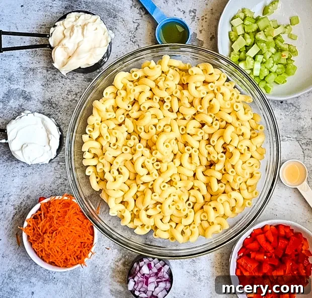 A bowl of creamy macaroni salad, featuring vibrant bell peppers and celery, ready for a summer picnic.