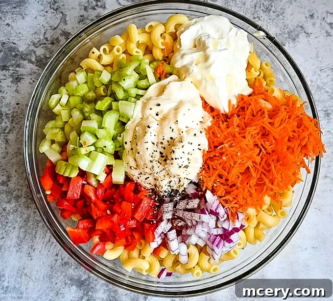 Close-up of macaroni salad with a focus on its creamy dressing and visible fresh ingredients, highlighting its appetizing texture.