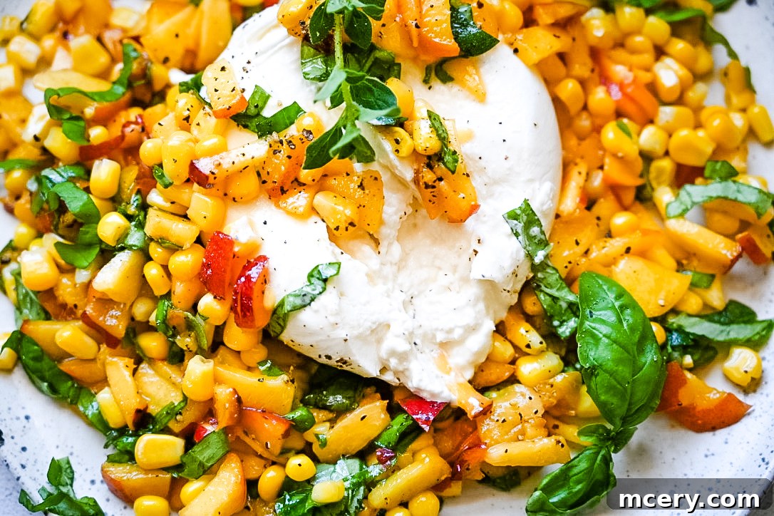 A beautifully plated Peach, Corn & Burrata Salad with vibrant peaches, yellow corn kernels, green herbs, and a creamy ball of burrata cheese.