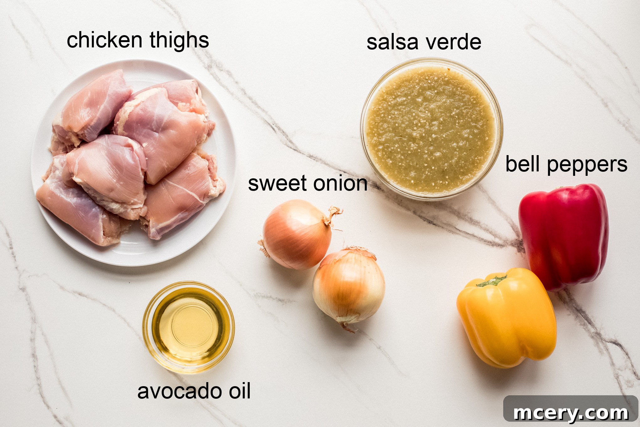Sizzling Chicken Fajita Bowl 4 A curated selection of fresh ingredients laid out for the chicken fajita bowl recipe, including chicken thighs, jarred salsa verde, colorful bell peppers, and an onion.