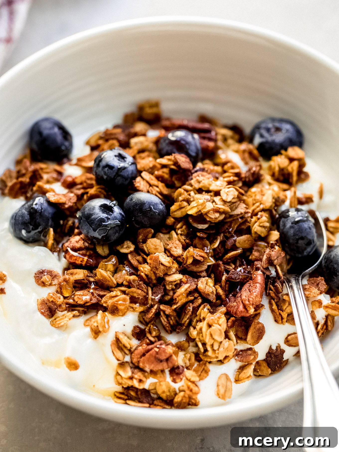 A bowl of freshly baked pumpkin granola with visible spices and pecans, ready to be enjoyed.