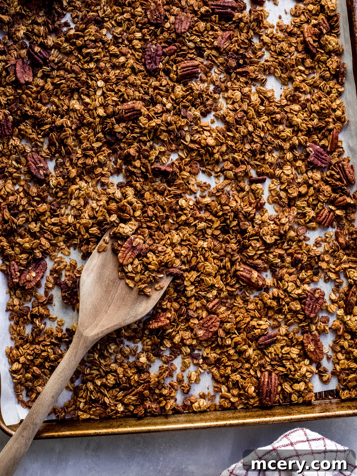 A large batch of golden-brown pumpkin pecan granola cooling on a baking sheet, showcasing its crunchy texture.