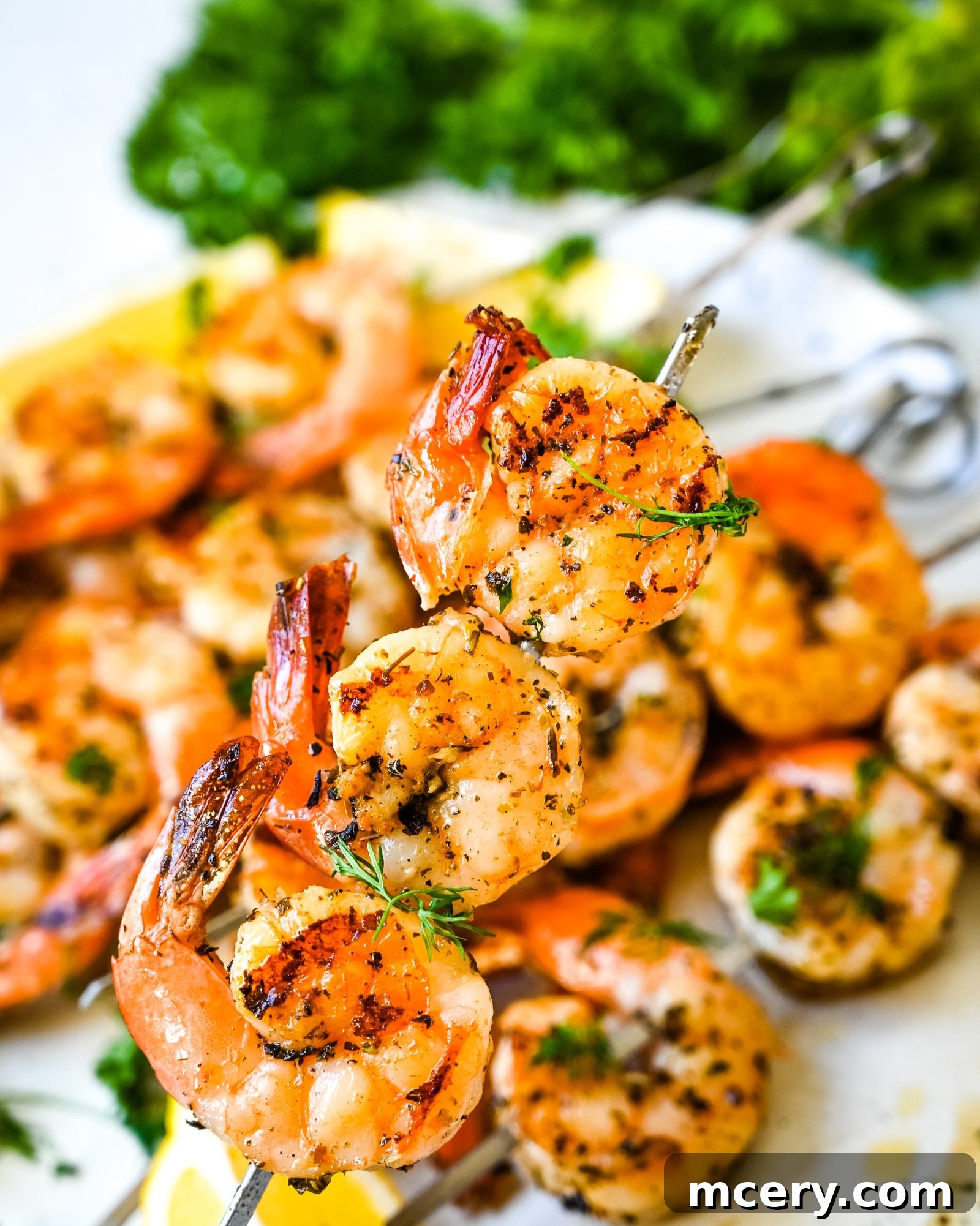 Chargrilled Garlic Herb Shrimp Skewers 4 Ingredients for Garlic Herb Grilled Shrimp Skewers laid out on a countertop: raw shrimp, fresh herbs, lemon, garlic, and seasoning.