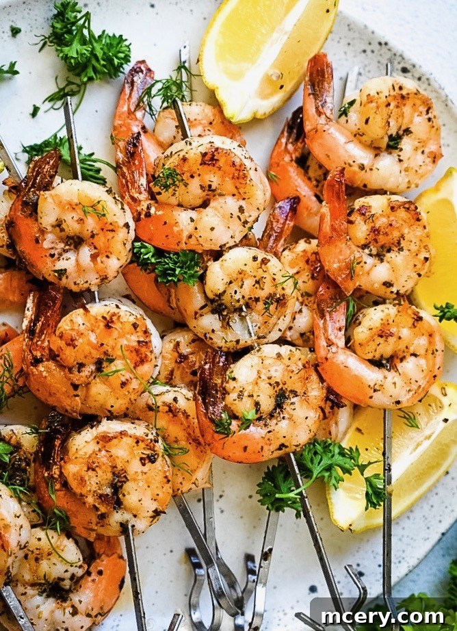 Close-up of Garlic Herb Grilled Shrimp Skewers garnished with fresh herbs. The shrimp appear to be seasoned with spices and herbs, showing a slightly charred texture. Lemon wedges are placed in the top right corner, adding a vibrant and fresh contrast to the dish.