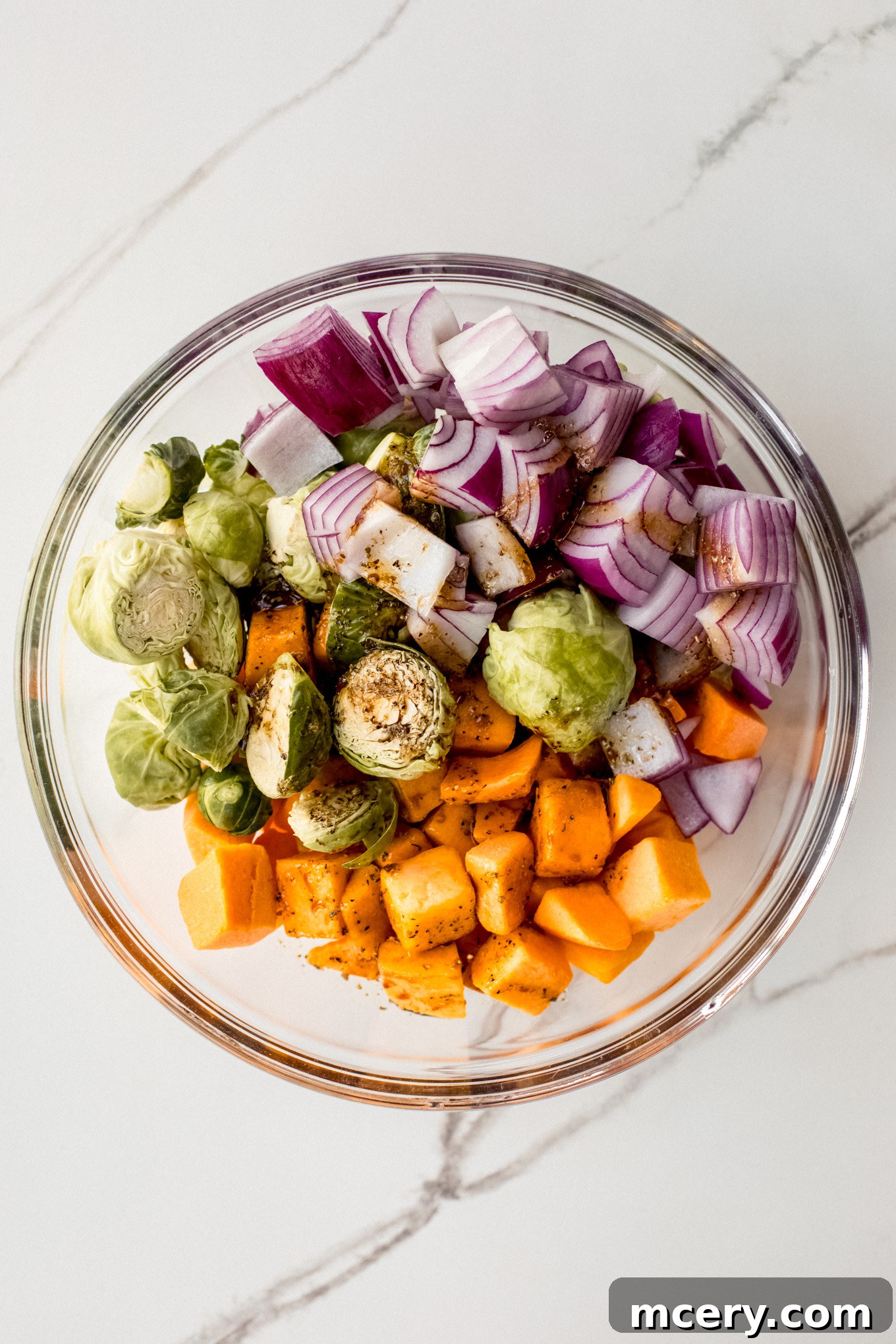 Autumn Roasted Bounty 6 Cut vegetables being tossed with the oil and vinegar mixture in a glass bowl.