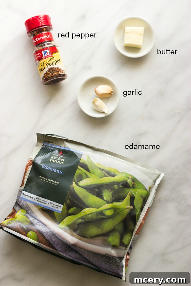 Fiery Garlic Edamame 3 Individual ingredients for spicy garlic edamame laid out: frozen edamame, butter, garlic cloves, and red pepper flakes.
