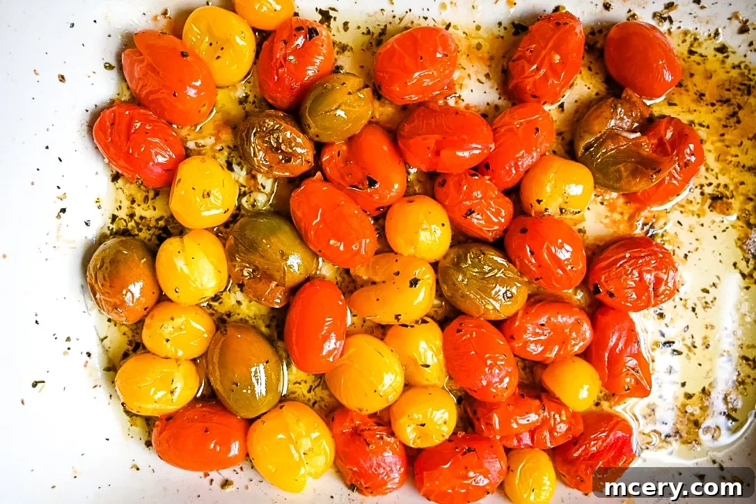 Roasted tomatoes bubbling in the oven, their skins slightly burst and flavors concentrated.