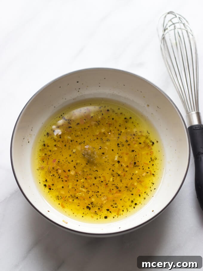 Harvest Apple Brussels Sprout Salad 4 salad vinaigrette in a bowl with a side of whisk.