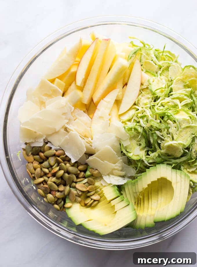 Harvest Apple Brussels Sprout Salad 5 chopped up ingredients in a glass bowl for the brussels sprouts salad.