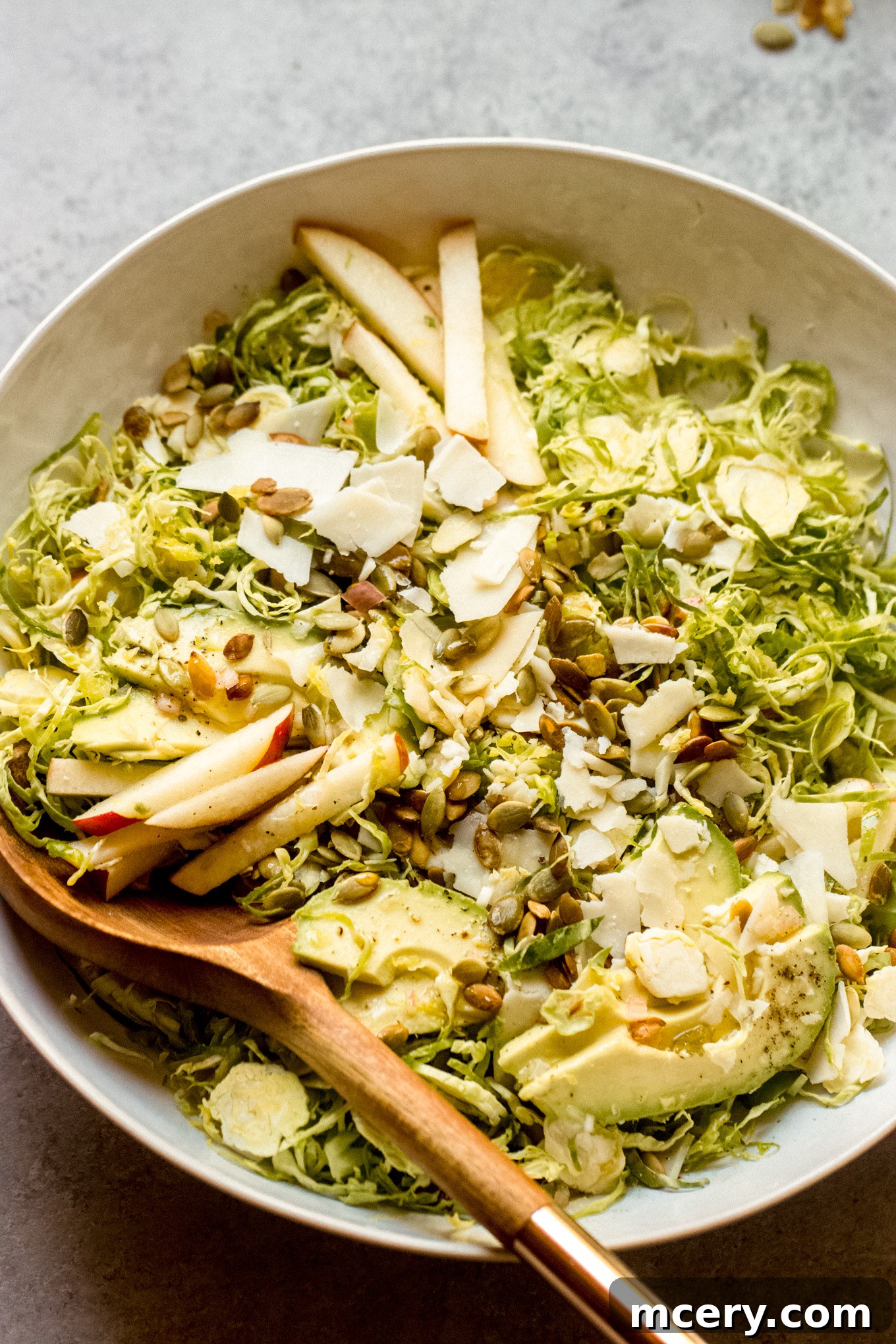 Harvest Apple Brussels Sprout Salad 8 salad with shredded Brussels sprouts with sliced apples and avocado in a bowl.