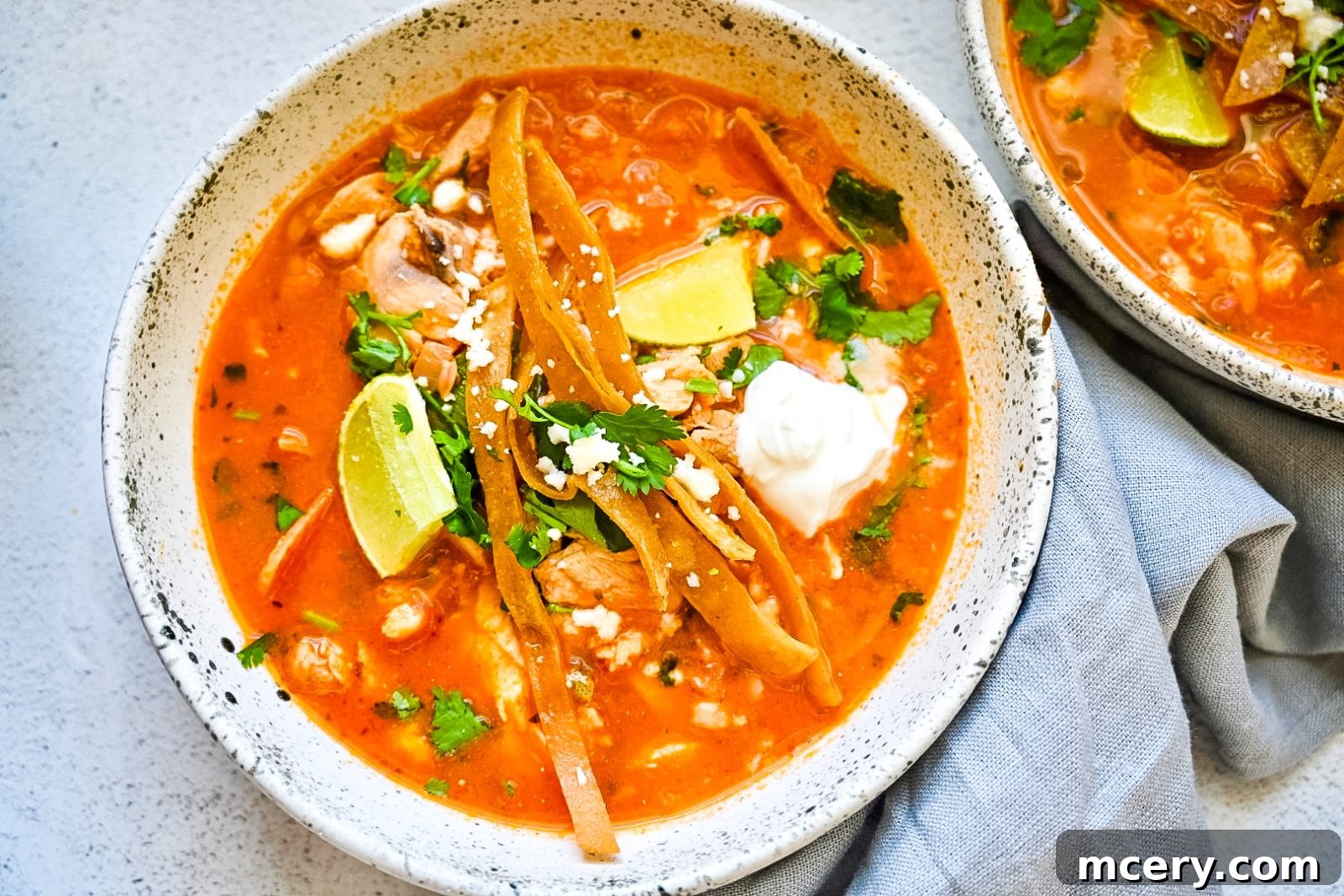 Speedy Southwestern Chicken Tortilla Soup 4 A close-up of a serving of Easy Chicken Tortilla Soup in a bowl, showing the rich broth, shredded chicken, white beans, and fresh toppings.