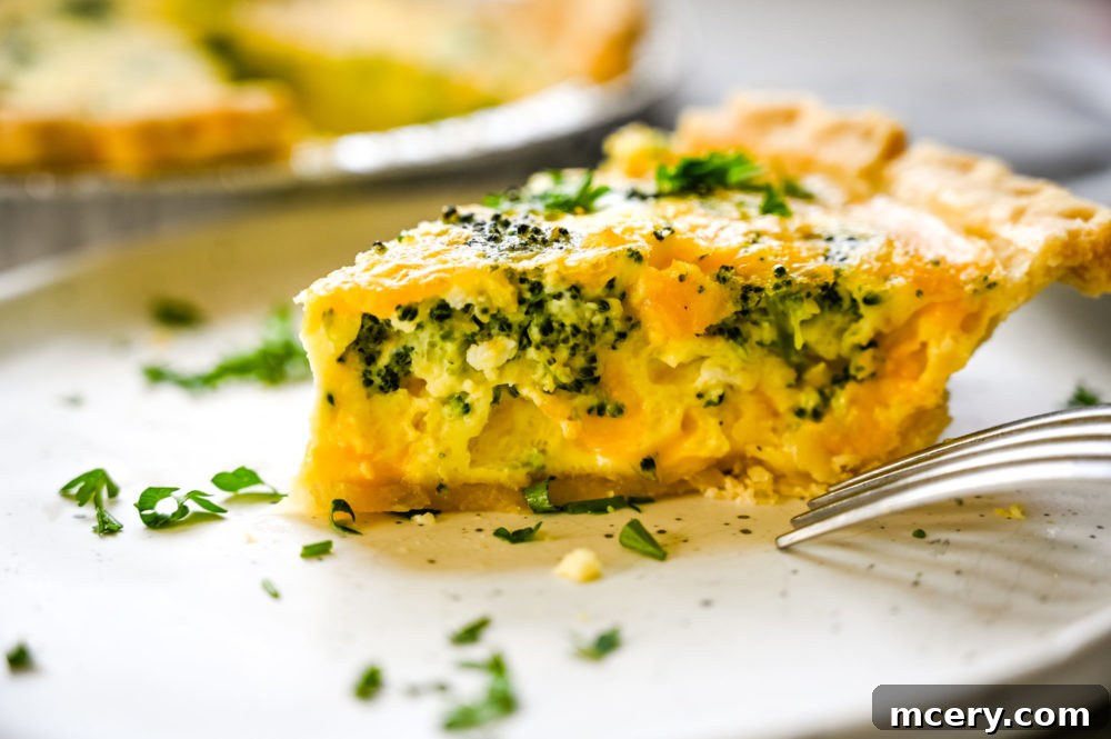 A slice of quiche served on a plate with a fork.