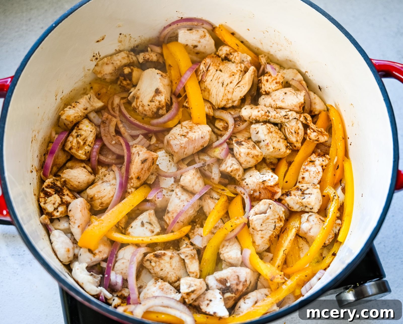 Bold One-Pot Cajun Chicken Pasta 5 Diced chicken breast being seasoned with Cajun spices in a pan.