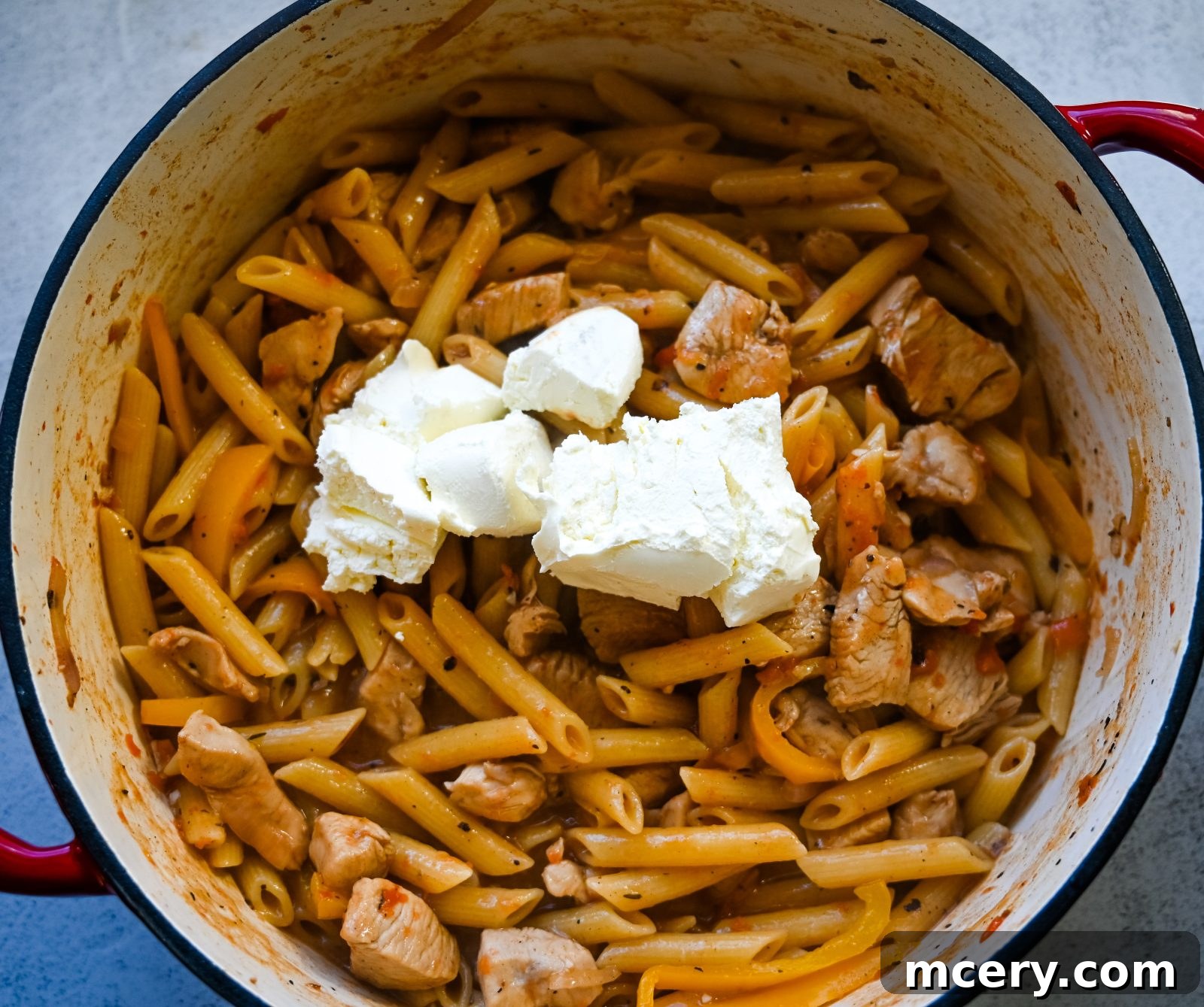 Bold One-Pot Cajun Chicken Pasta 7 Adding pasta, chicken broth, and fire-roasted tomatoes to the pot.