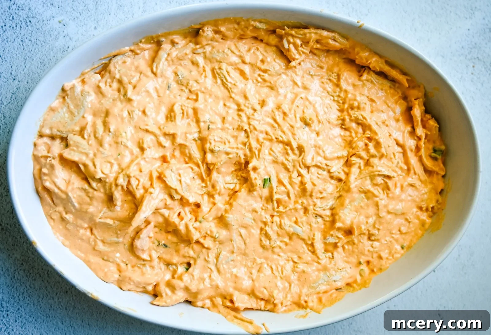 Ultimate Game Day Chicken Dip 9 Buffalo Chicken Dip in a rustic baking dish on a wooden surface.