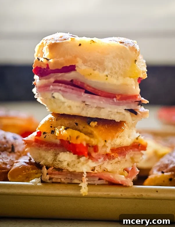 Italian Deli Sliders 6 Mozzarella cheese slices being placed over the meat layers on Italian Sandwich Sliders.