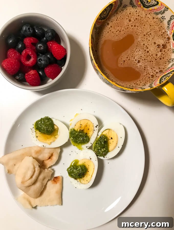 Hard-boiled eggs topped with basil pesto, fresh berries, and coffee with coconut cream – a simple and protein-rich breakfast.
