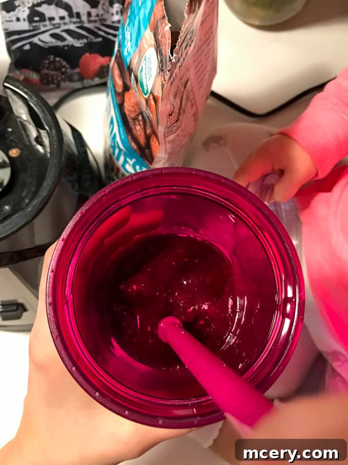 A child's hand reaching for a refreshing berry smoothie, illustrating shared healthy habits.