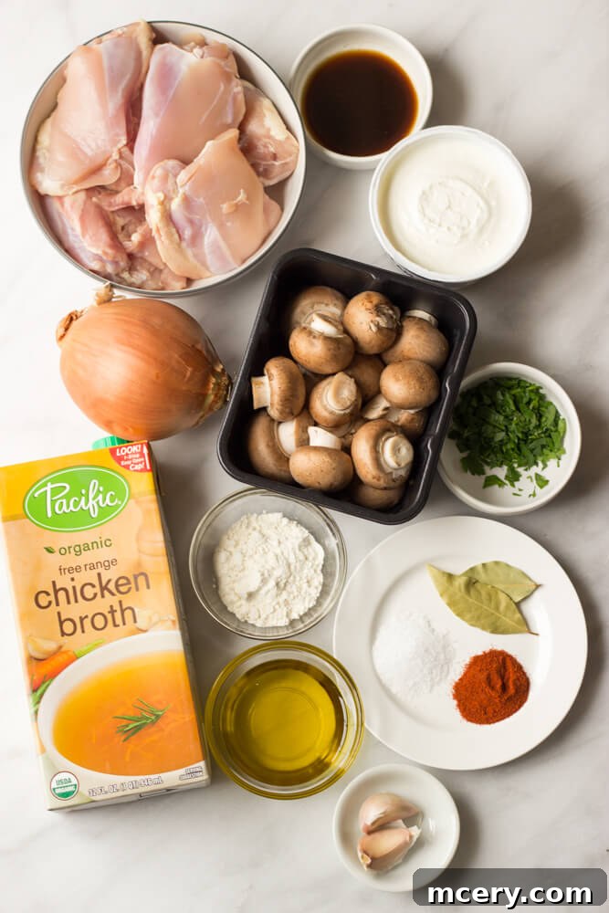 A selection of fresh ingredients for chicken stroganoff, including mushrooms, chicken, and herbs.