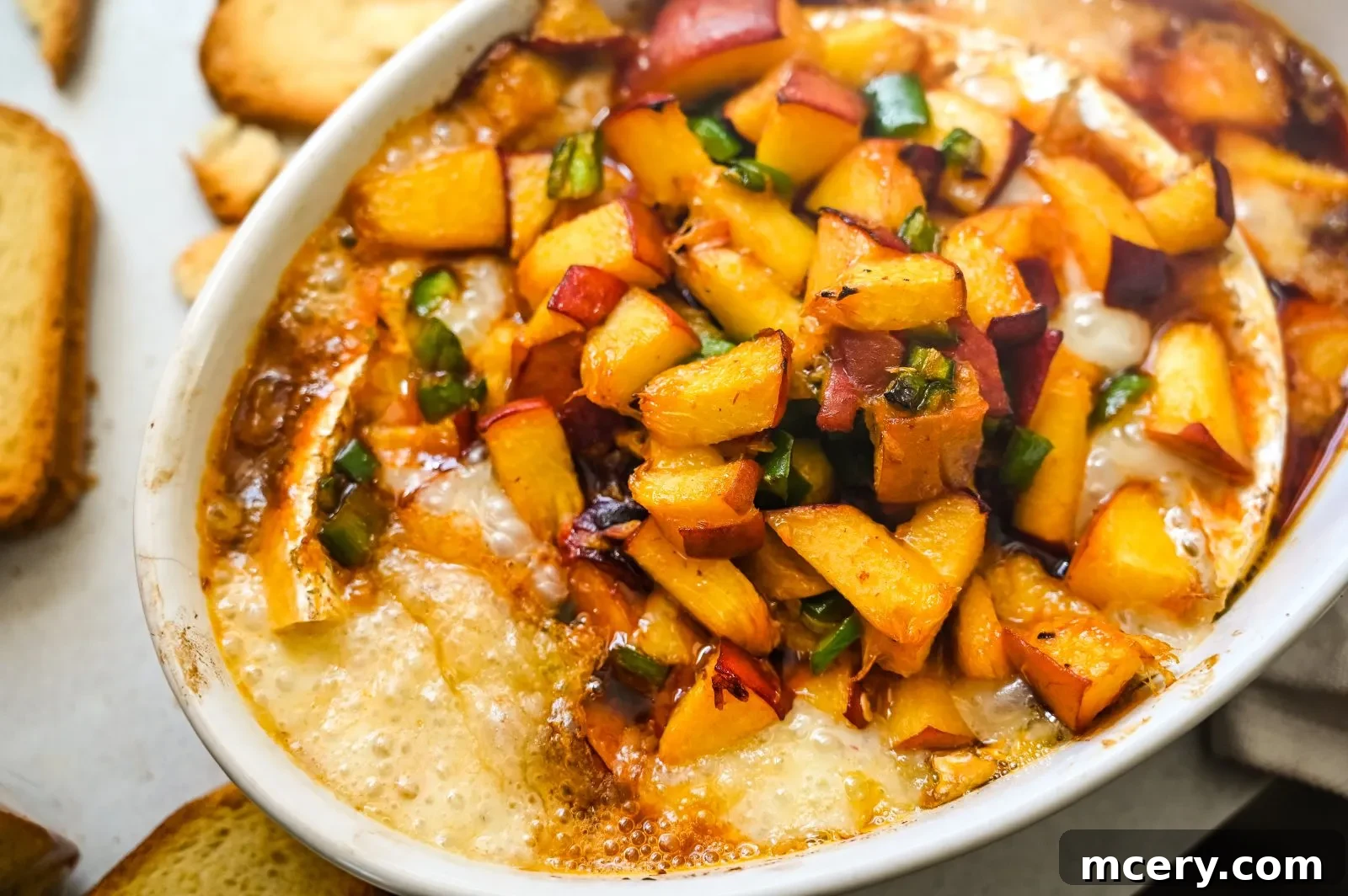 Baked Brie with Sweet Peach and Smoky Chipotle 3 A close-up of Honey Peach & Chipotle Baked Brie, showcasing the melted cheese and a vibrant peach-chipotle topping.