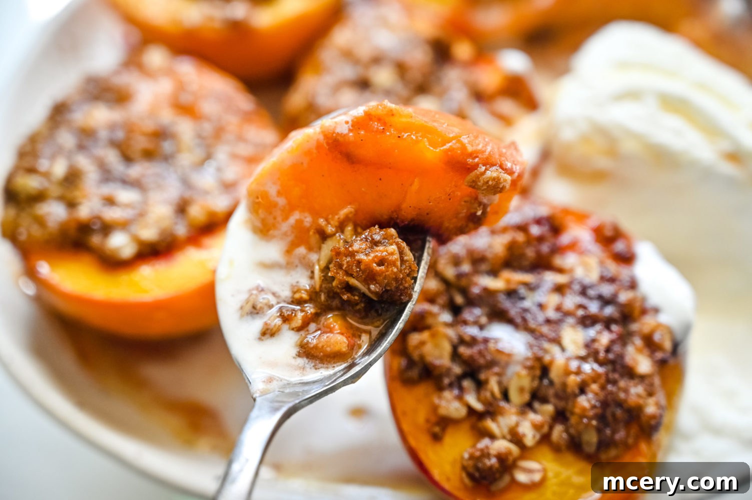 Sun-Kissed Peach Crumble 3 Close-up of baked peach halves in a baking dish, each filled with a crumbly oat topping, showcasing their golden-brown edges and soft texture.