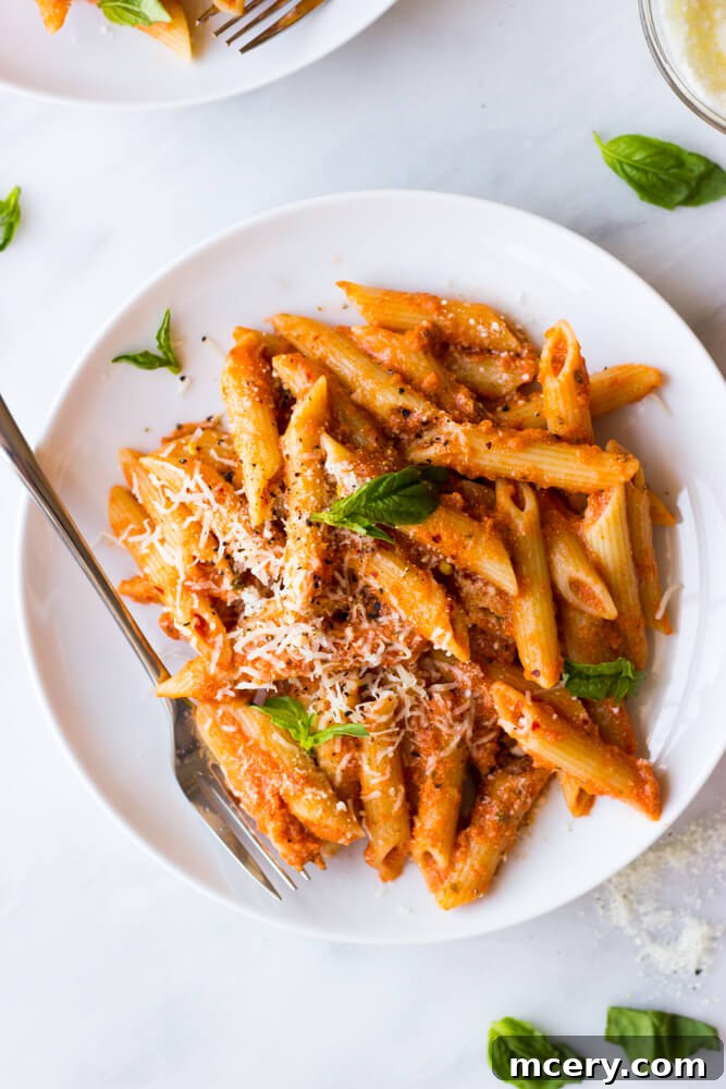 Creamy Vodka Pasta Perfection 6 A beautifully plated bowl of creamy pink vodka sauce pasta, expertly garnished with a sprinkle of fresh basil and grated Parmesan cheese, ready to be savored.