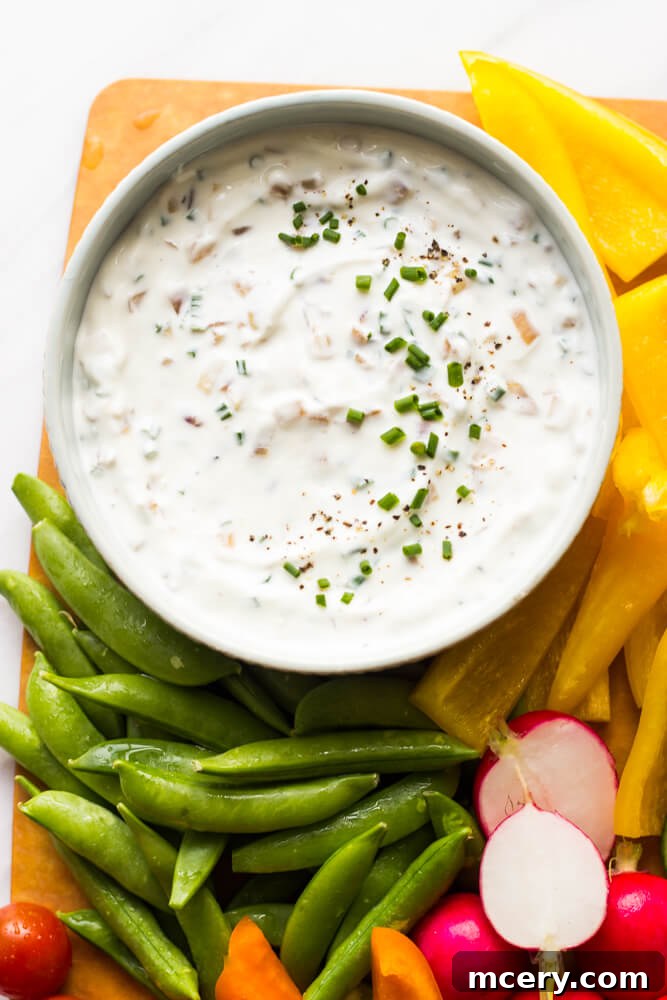 Tangy Greek Yogurt Onion Dip 3 Close-up shot of creamy Greek yogurt french onion dip in a white bowl, garnished with fresh chives.