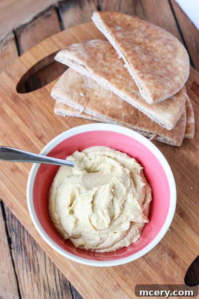 A selection of warm pita pockets artfully arranged around a bowl of creamy hummus, inviting you to create the perfect stuffed meal.