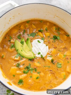 A large Dutch oven brimming with creamy chicken apple chili, garnished beautifully, ready to be served.