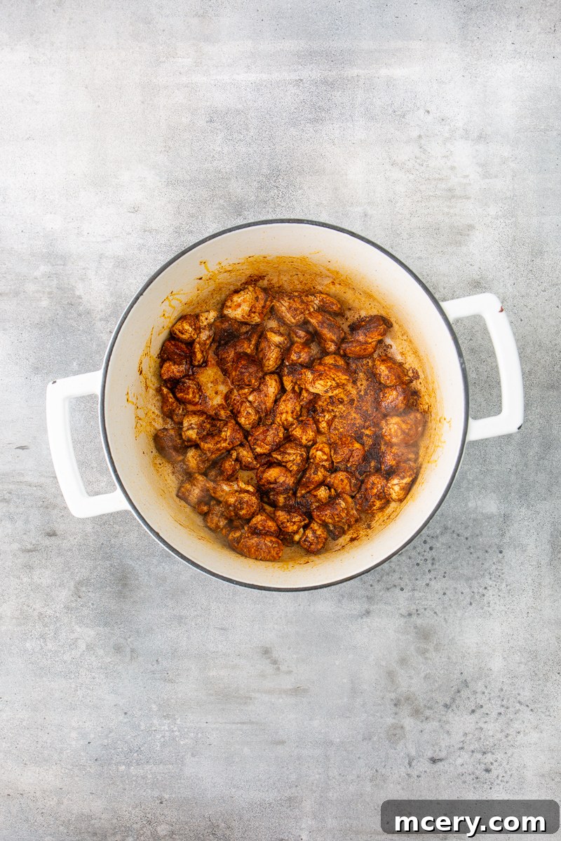 Sweet and Savory Chicken Apple Chili 4 Cooked chicken tenders seasoned with chili powder and cumin, simmering in a large Dutch oven, ready to be transferred.