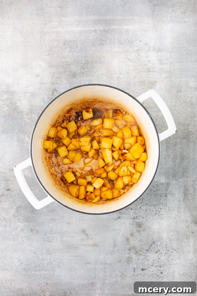 Sweet and Savory Chicken Apple Chili 5 Tender, golden-brown apple chunks and diced onions sautéing in a Dutch oven, releasing their sweet aromas.