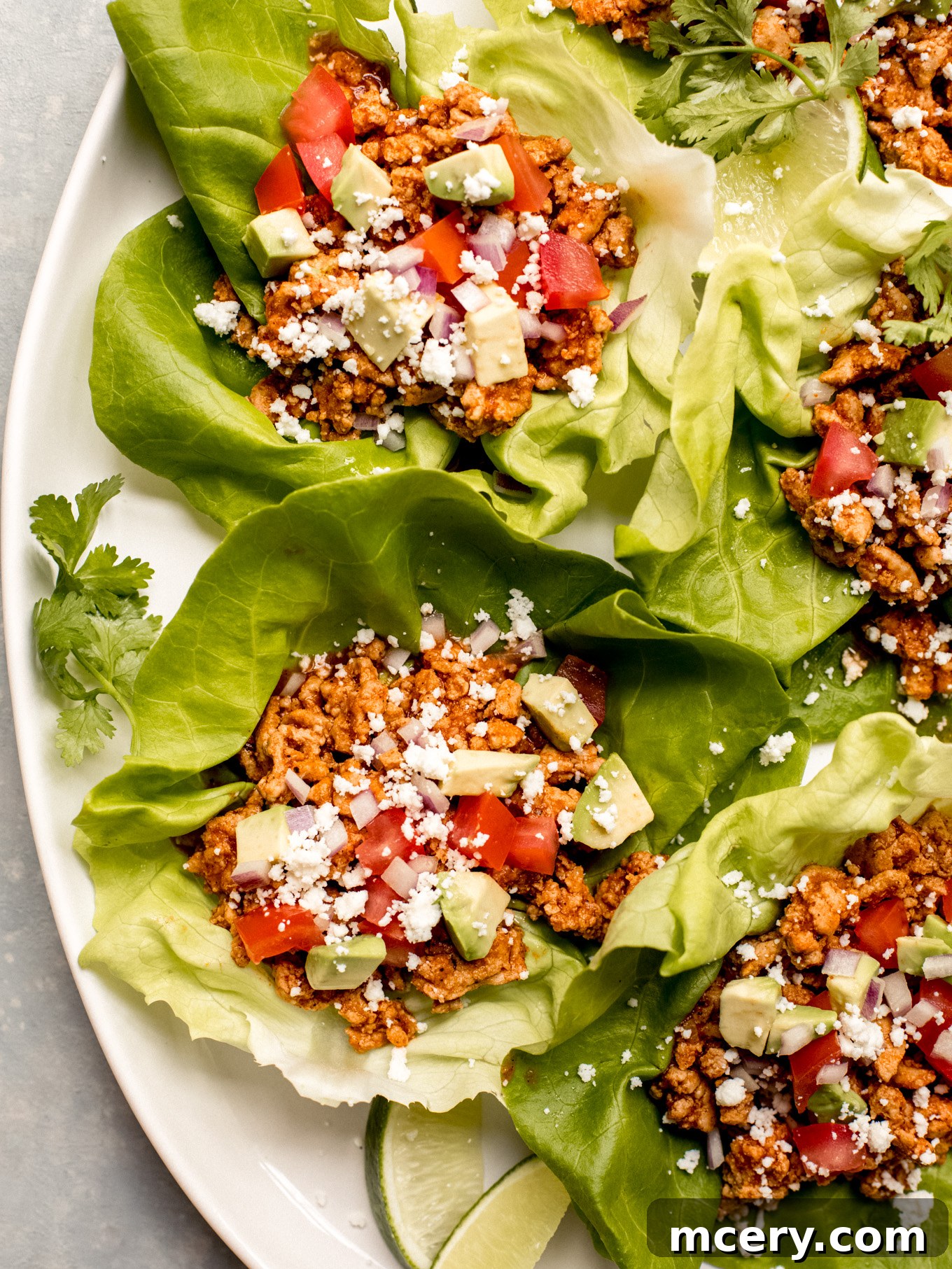 A close-up shot of a single turkey lettuce wrap taco on a platter with toppings