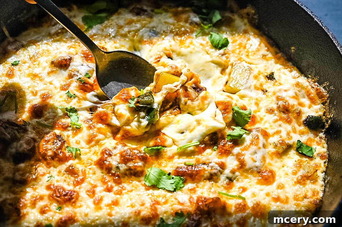 Irresistible Queso Fundido 2 QUESO FUNDIDO - a hot skillet of melted Mexican cheese, poblano peppers, and potatoes, ready to be scooped with tortilla chips.