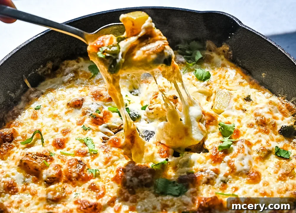 Irresistible Queso Fundido 3 Close-up of Queso Fundido with a spoon, showing the gooey texture and visible poblano pieces.