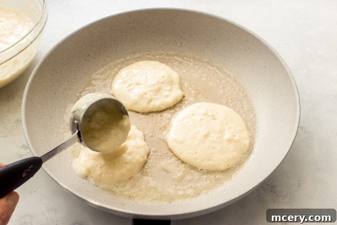 Ricotta pancakes sizzling in a non-stick skillet