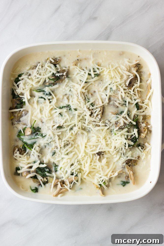 Creamy Chicken Lasagna with Spinach and Mushrooms 10 Assembled chicken lasagna covered with foil in a white baking dish, ready for baking.
