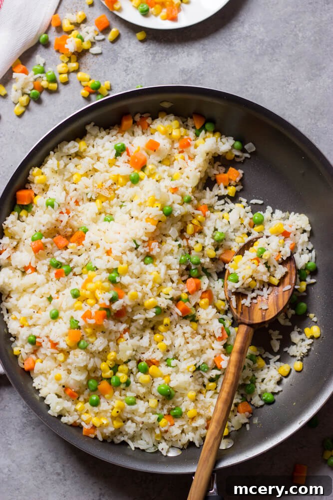 Flavorful Mexican White Rice 5 Close-up of fluffy Mexican white rice generously mixed with vibrant corn and peas, showcasing its inviting texture and appealing colors.