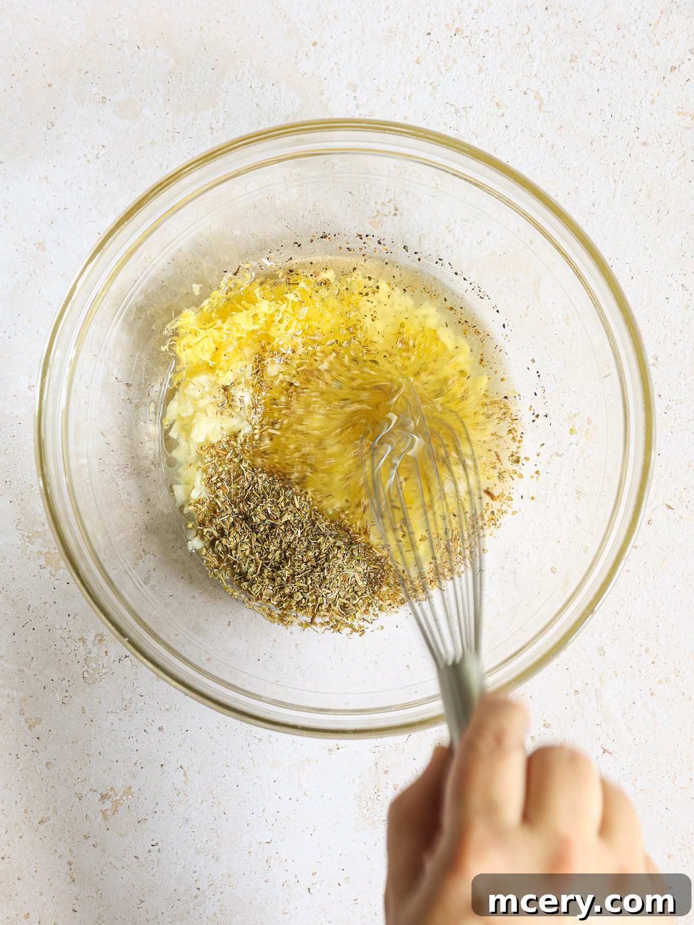 Homemade Chicken Gyro Perfection 4 Whisking lemon garlic marinade ingredients in a glass bowl.