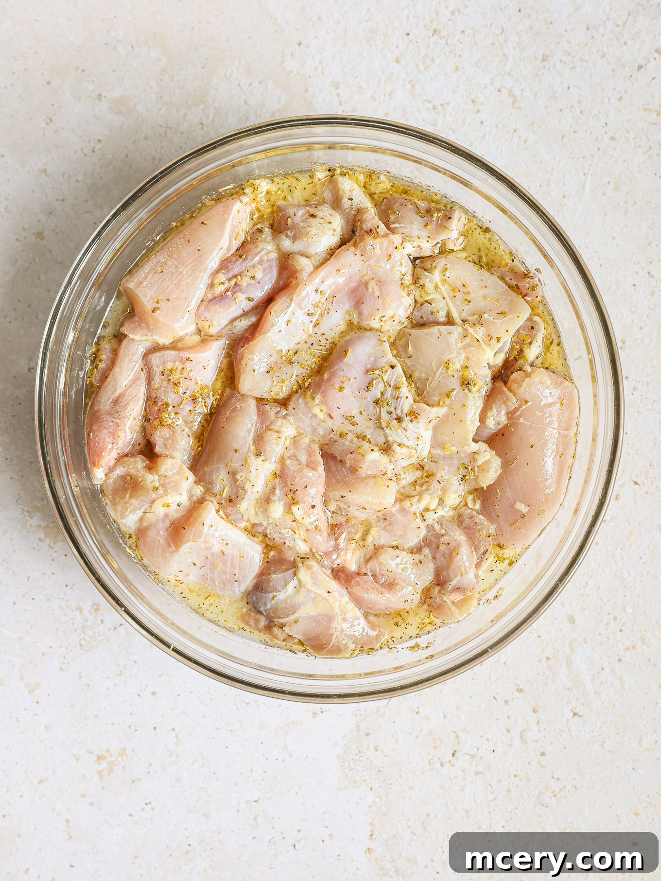 Homemade Chicken Gyro Perfection 5 Chicken thigh chunks coated in lemon marinade in a glass bowl.