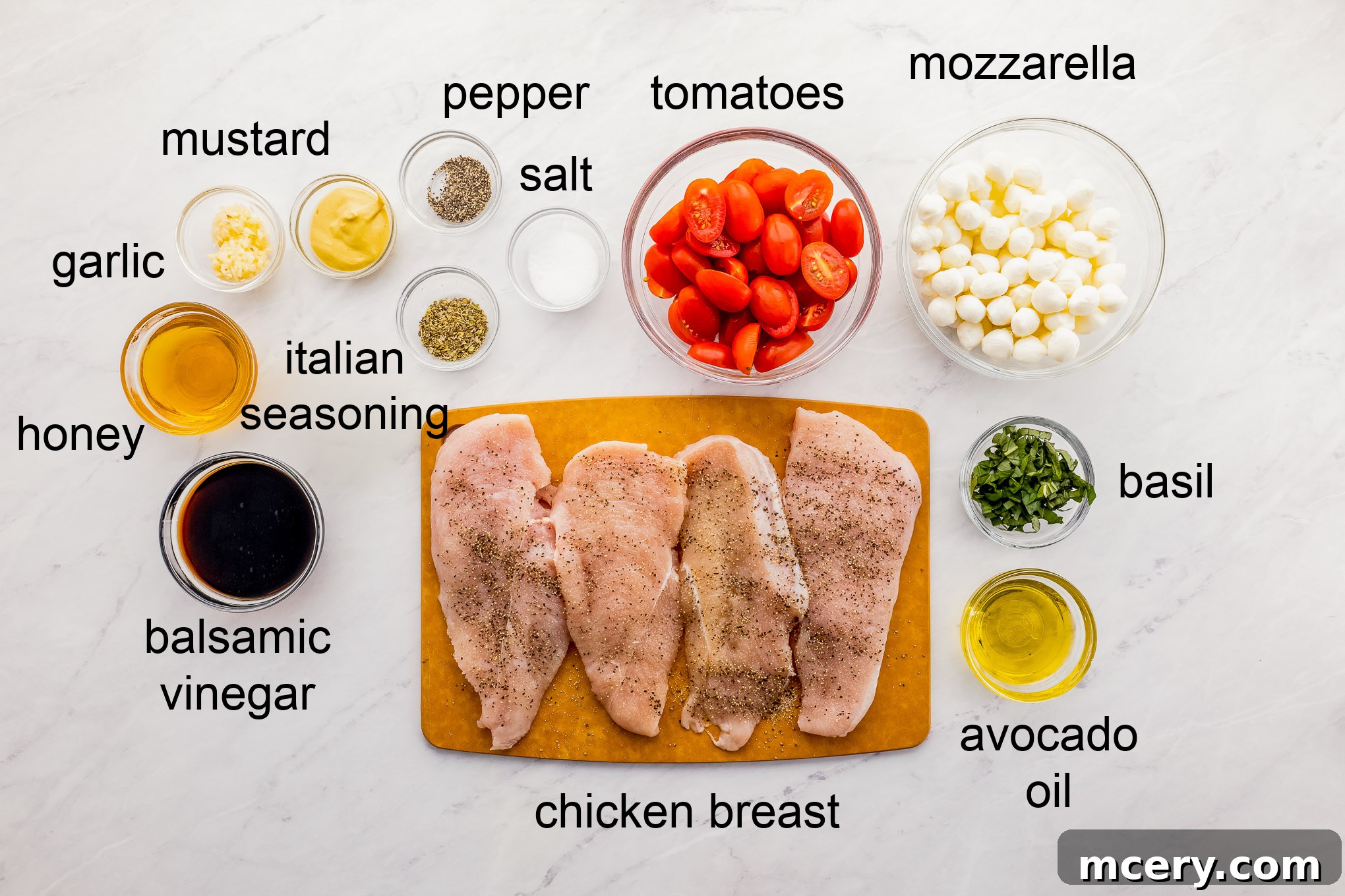 All the fresh ingredients for one pan balsamic chicken laid out on a cutting board, including chicken breast, balsamic vinegar, tomatoes, mozzarella, and basil.